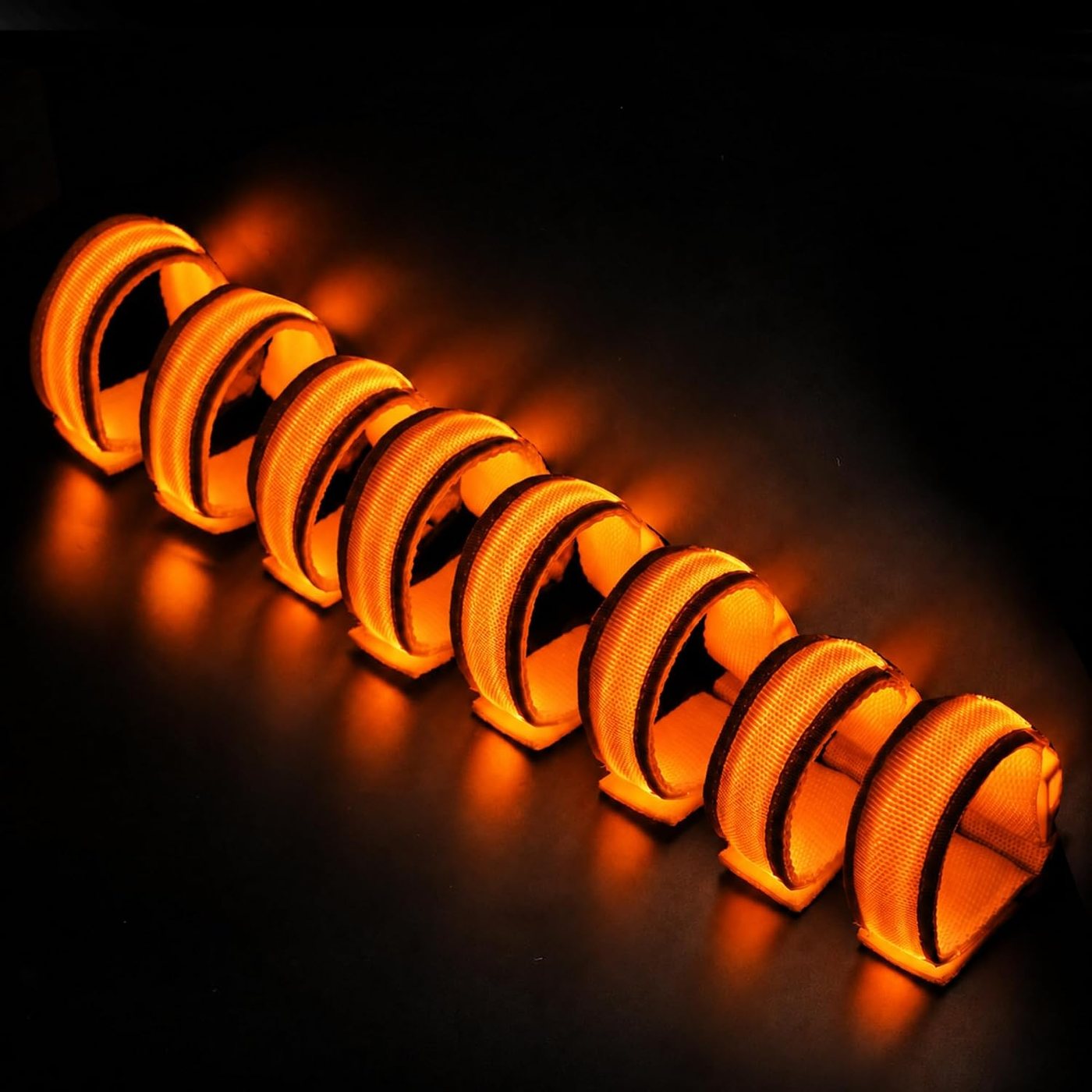 A stack of orange FANL glow bracelets lit in the dark
